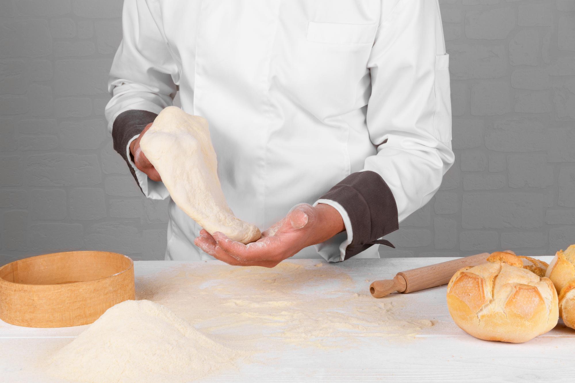 Chef hands shaping dough on floured board